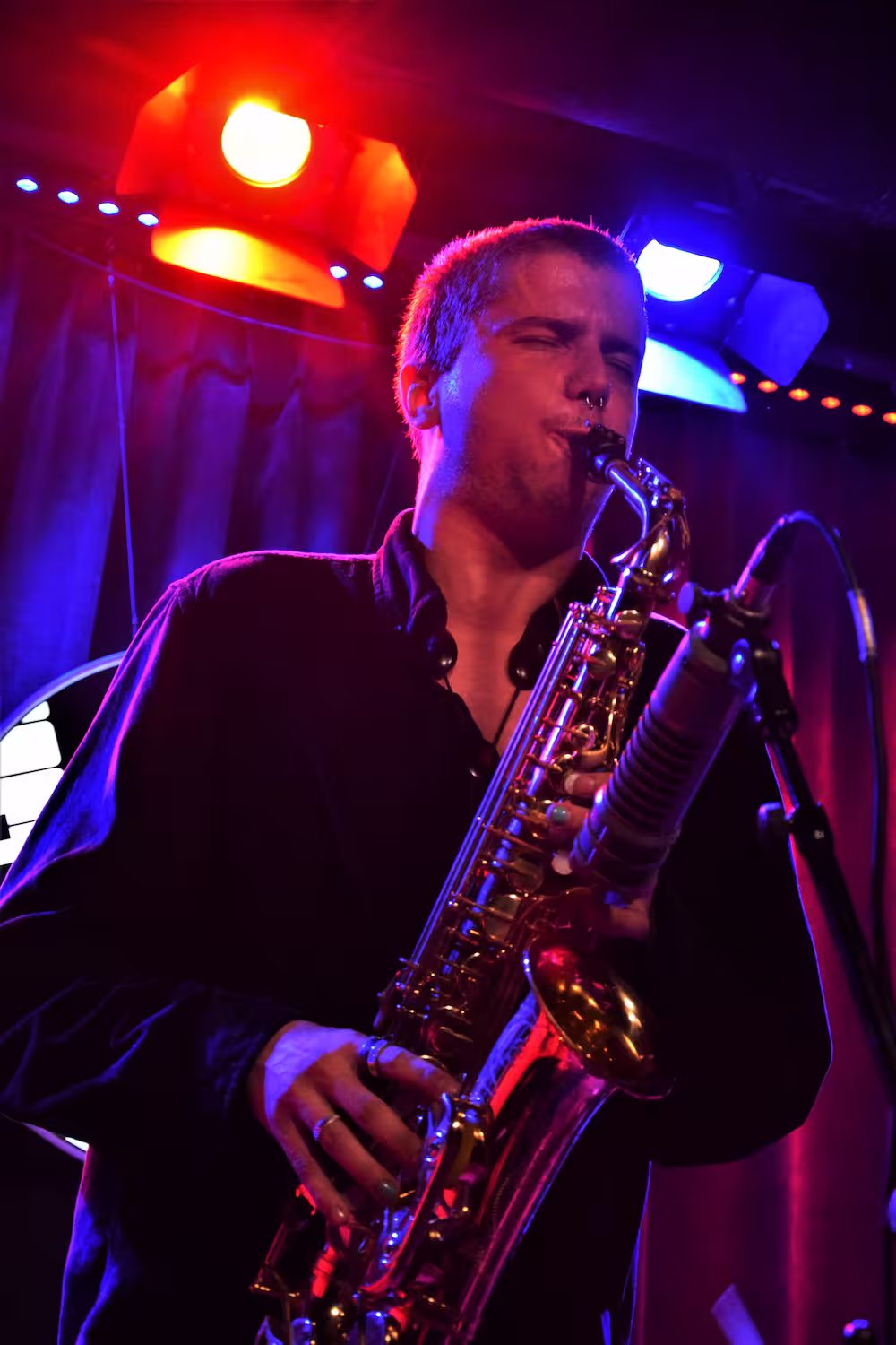 Martynas playing his saxophone in a club-like place, looking to the right of the frame.